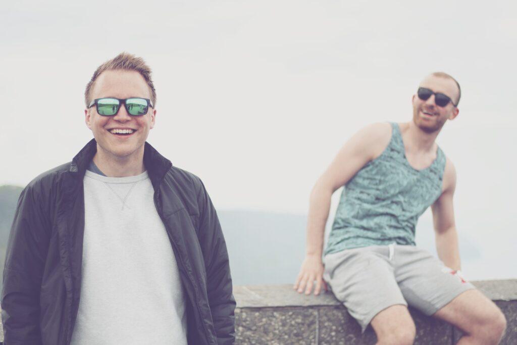 Two Men In Sunglasses Chilling Near Lake
